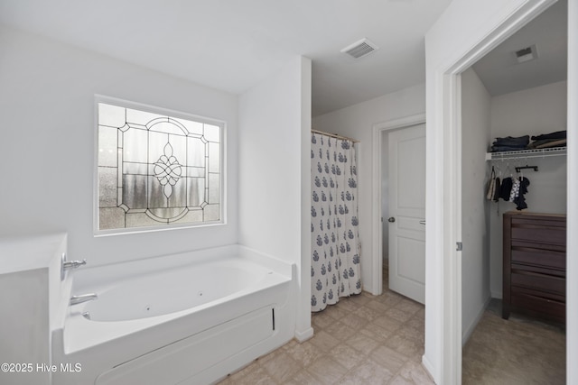 full bathroom featuring baseboards, a spacious closet, visible vents, and a whirlpool tub