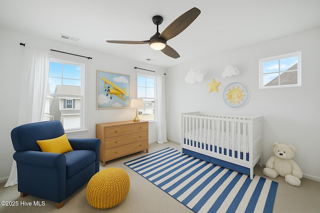 carpeted bedroom with a nursery area, visible vents, and a ceiling fan