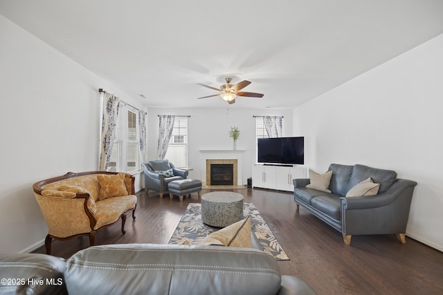 living area with baseboards, wood finished floors, a ceiling fan, and a fireplace with flush hearth