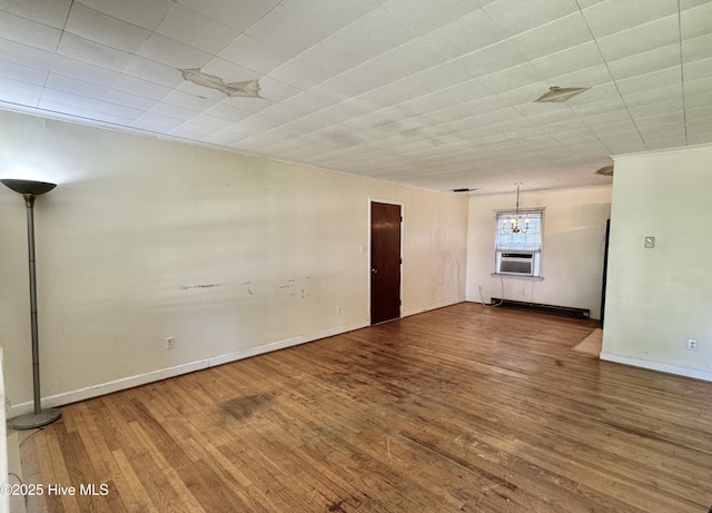 spare room with baseboards, wood finished floors, and cooling unit