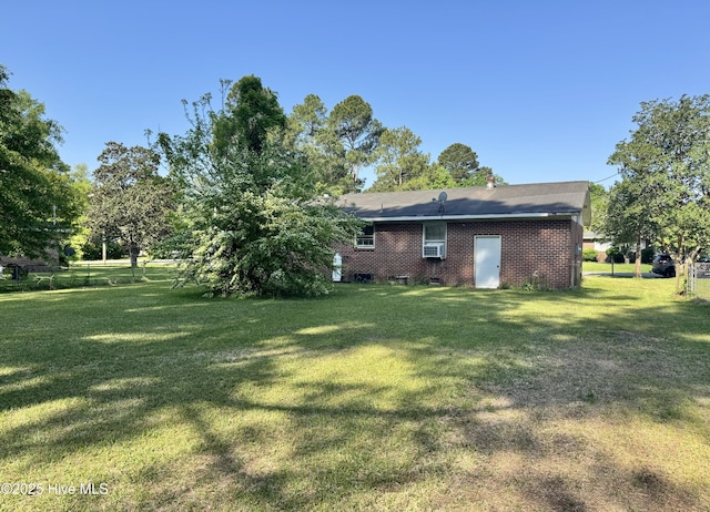 rear view of house with brick siding and a yard