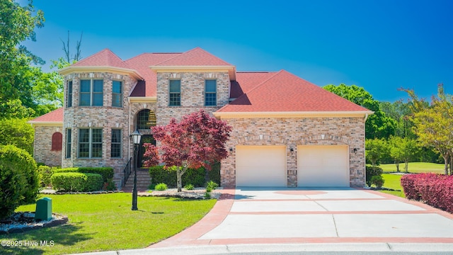 view of front of property featuring an attached garage, driveway, and a front lawn