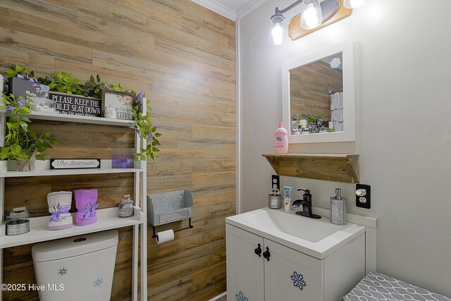 bathroom featuring crown molding, wood walls, and vanity