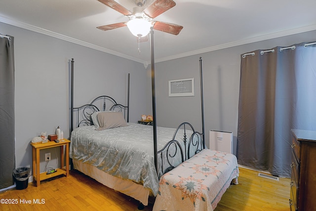bedroom with crown molding, wood finished floors, a ceiling fan, and visible vents