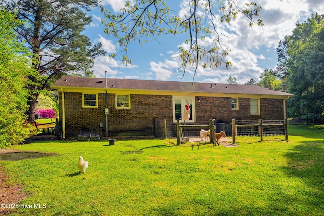 back of house with a yard, brick siding, and fence