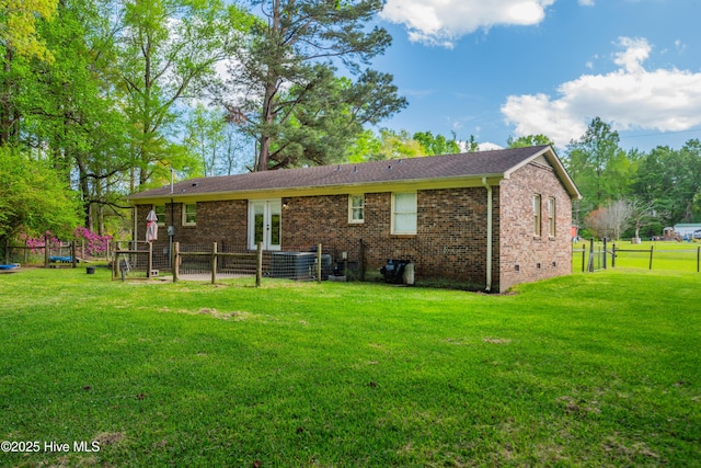 back of property featuring french doors, brick siding, fence, and a yard