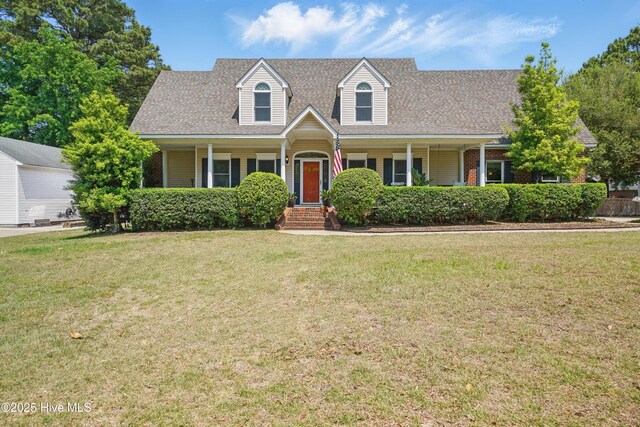 cape cod home featuring a porch, a shingled roof, a front lawn, and brick siding