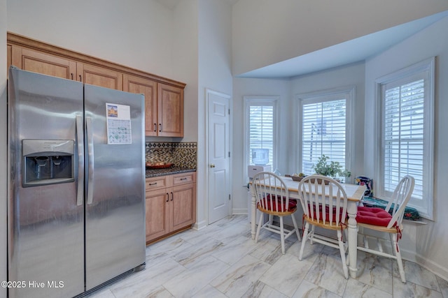 5029 Woods Edge Rd, Wilmington, NC 28409 - kitchen with baseboards, brown cabinetry, a wealth of natural light, and stainless steel fridge with ice dispenser