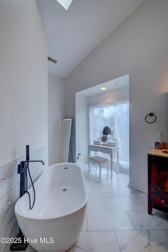 5029 Woods Edge Rd, Wilmington, NC 28409 - full bath featuring visible vents, vaulted ceiling, vanity, a freestanding bath, and marble finish floor