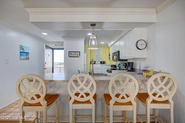 kitchen with black microwave, a sink, range with electric cooktop, a peninsula, and ornamental molding