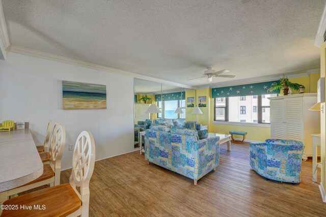 living room featuring crown molding, a textured ceiling, ceiling fan, and wood finished floors