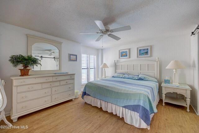 bedroom with baseboards, a textured ceiling, ceiling fan, and light wood-style flooring