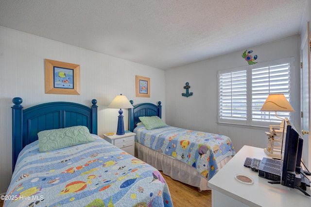 bedroom with a textured ceiling and light wood-style floors