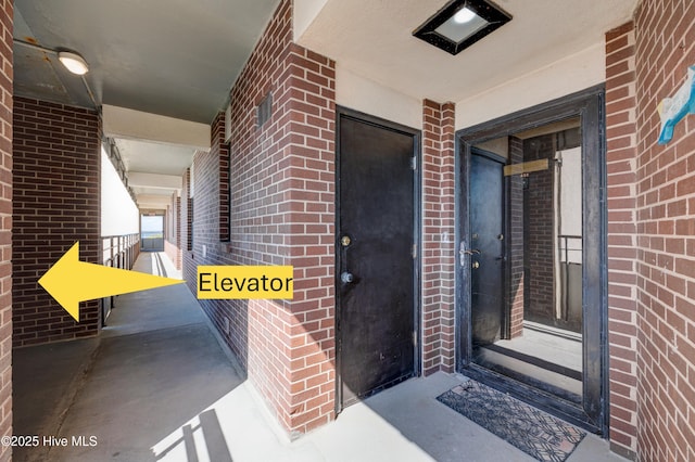 doorway to property featuring brick siding