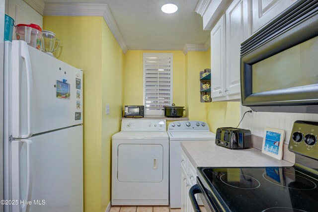 laundry room with crown molding, laundry area, light tile patterned floors, and washing machine and clothes dryer