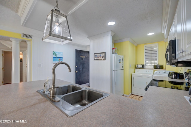 kitchen with independent washer and dryer, a sink, freestanding refrigerator, visible vents, and ornamental molding