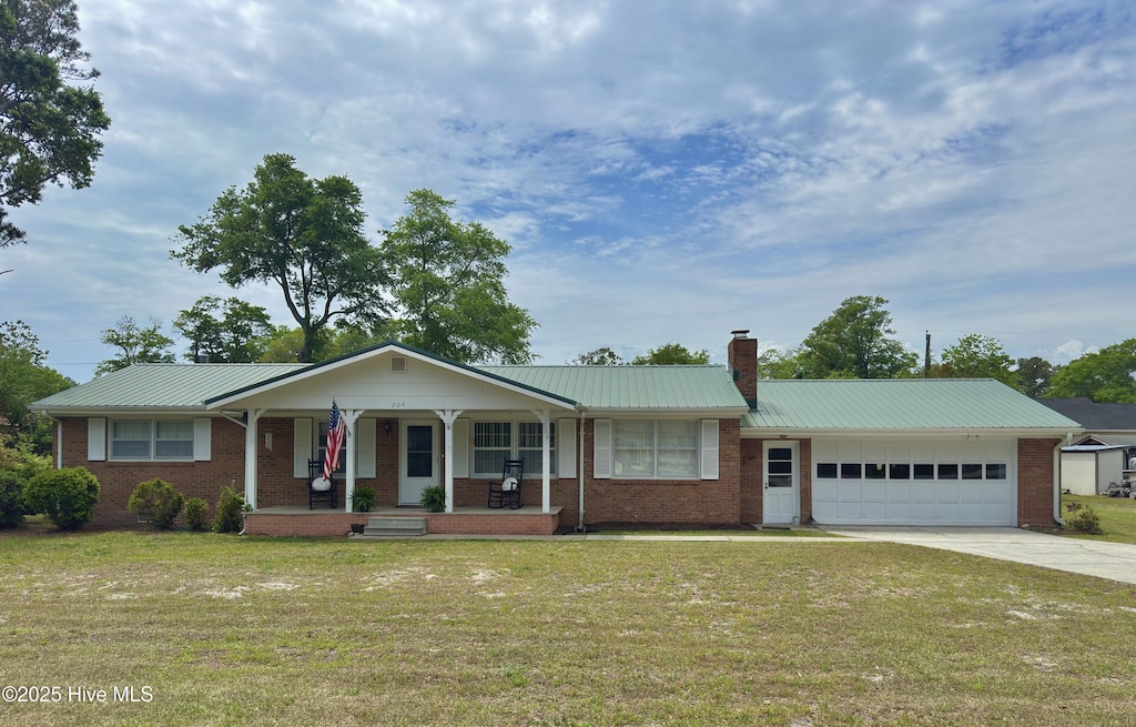 ranch-style house with a garage, a front lawn, concrete driveway, metal roof, and a porch
