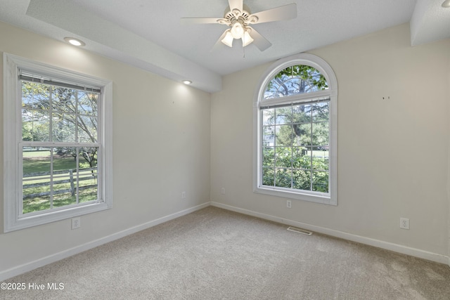 carpeted empty room with visible vents, baseboards, and ceiling fan