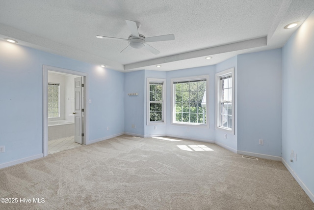 carpeted spare room with visible vents, ceiling fan, baseboards, and a textured ceiling