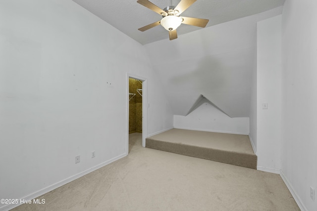 carpeted spare room with ceiling fan, baseboards, and lofted ceiling