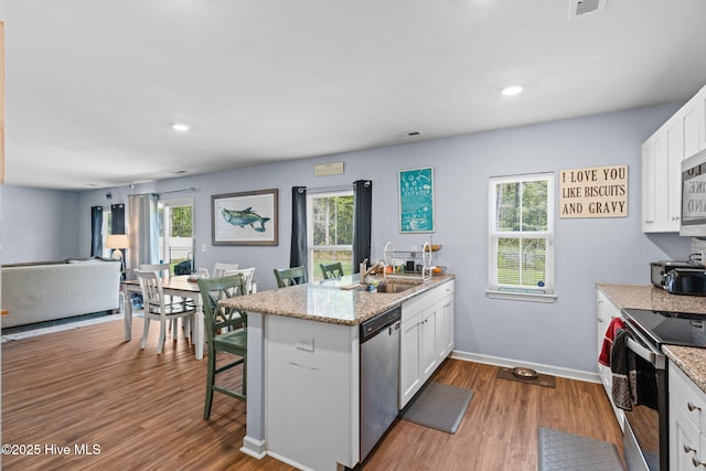 4333 Jones St SW, Shallotte, NC 28470 - kitchen with a peninsula, white cabinetry, wood finished floors, and stainless steel appliances