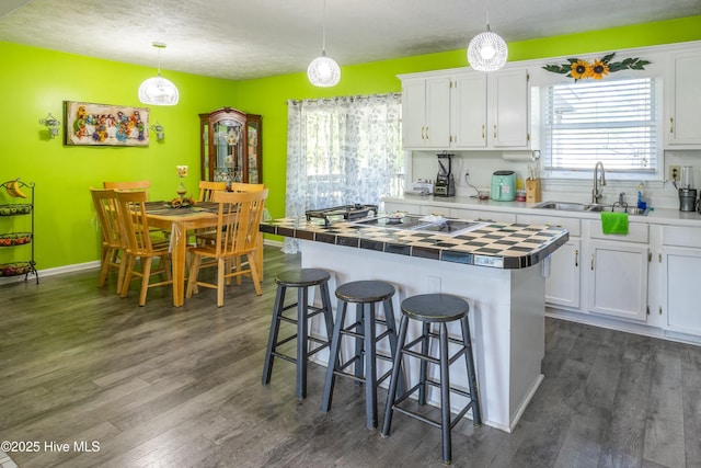 479 W 5th St, Garland, NC 28441 - kitchen featuring dark wood-style flooring, tile counters, white cabinets, a breakfast bar area, and a sink