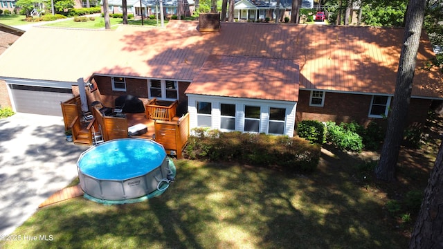 724 York St, Rocky Mount, NC 27803 - back of house with a deck, an outdoor pool, brick siding, concrete driveway, and a lawn