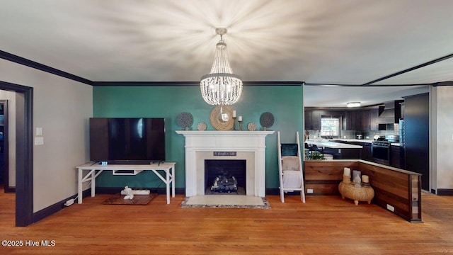 724 York St, Rocky Mount, NC 27803 - living room featuring light wood finished floors, a fireplace, a chandelier, baseboards, and ornamental molding