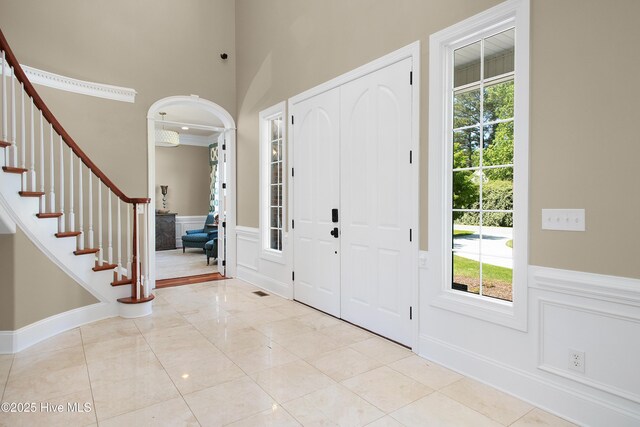 entryway featuring a decorative wall, a wainscoted wall, stairs, and plenty of natural light