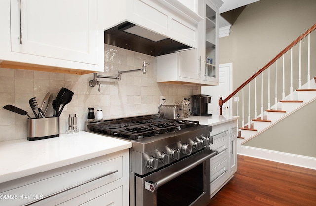 kitchen with glass insert cabinets, high end stove, white cabinetry, and tasteful backsplash