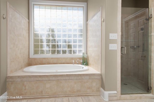 full bathroom featuring a shower stall, a garden tub, and baseboards