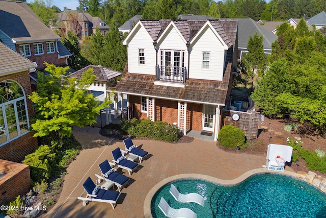 rear view of property with a patio area, an outdoor pool, an outdoor structure, brick siding, and a residential view