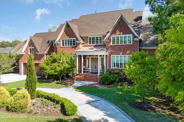 view of front of property with brick siding, an attached garage, a porch, and concrete driveway