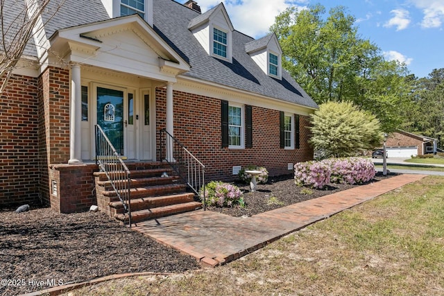 new england style home featuring crawl space, a shingled roof, and brick siding