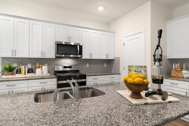 3048 Platinum Cir W, End, NC 27376 - kitchen with dark stone counters, tasteful backsplash, white cabinetry, a sink, and stainless steel appliances