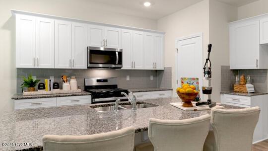 3048 Platinum Cir W, End, NC 27376 - kitchen with a sink, white cabinets, light stone counters, and stainless steel appliances