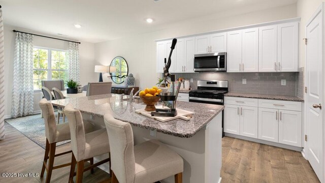 3048 Platinum Cir W, End, NC 27376 - kitchen featuring stainless steel appliances, light wood-style floors, a kitchen breakfast bar, and decorative backsplash