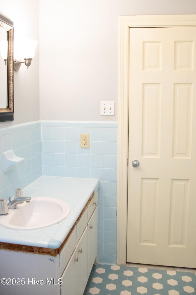 bathroom featuring tile patterned floors, vanity, tile walls, and a wainscoted wall