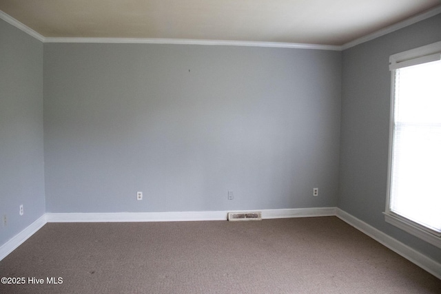 empty room featuring dark colored carpet, visible vents, baseboards, and crown molding