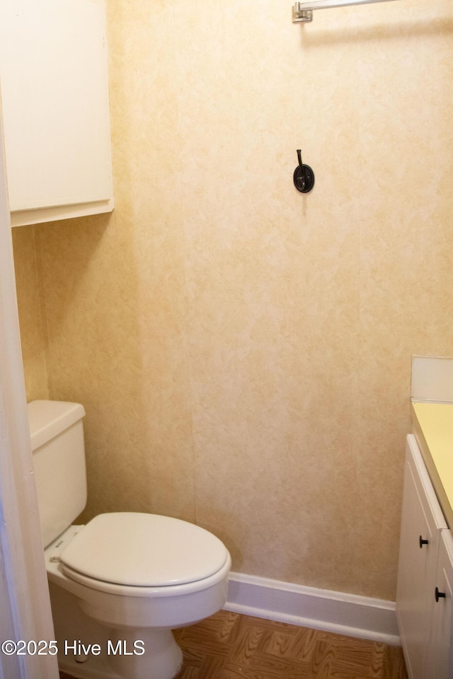 bathroom with toilet, vanity, and baseboards