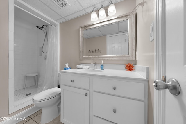 bathroom with a drop ceiling, toilet, a shower stall, vanity, and tile patterned floors