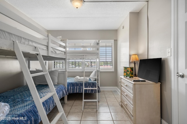 bedroom with baseboards, light tile patterned floors, and a textured ceiling