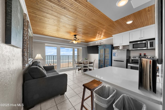 kitchen featuring appliances with stainless steel finishes, wood ceiling, light tile patterned floors, white cabinetry, and open floor plan