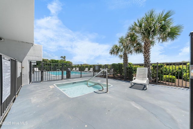community pool with a hot tub, a patio, and fence