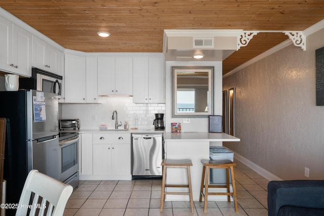 kitchen featuring stainless steel appliances, wooden ceiling, a sink, light tile patterned floors, and light countertops