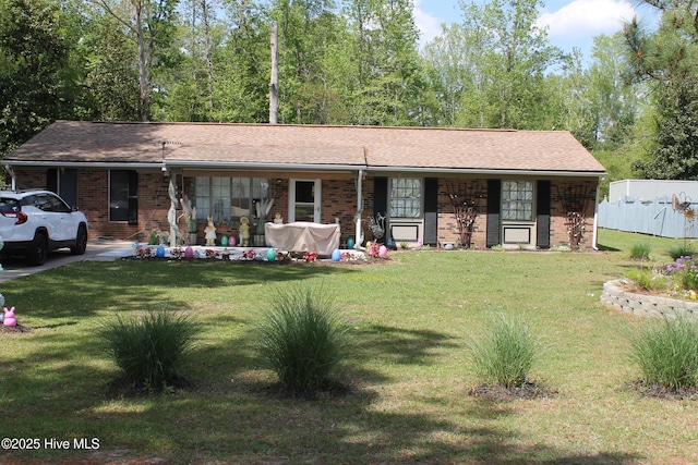 ranch-style home featuring a front yard, brick siding, and fence