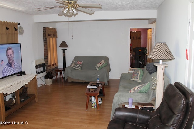 living room featuring a textured ceiling, wood finished floors, ceiling fan, and heating unit