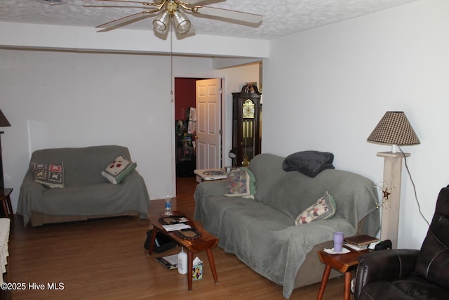 living area with a ceiling fan, wood finished floors, and a textured ceiling