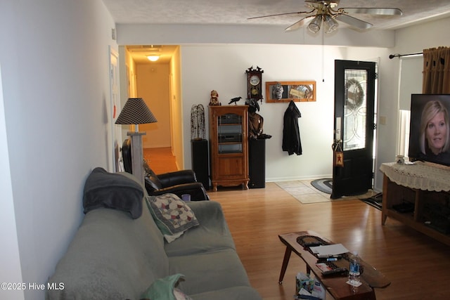 living area with a ceiling fan and wood finished floors