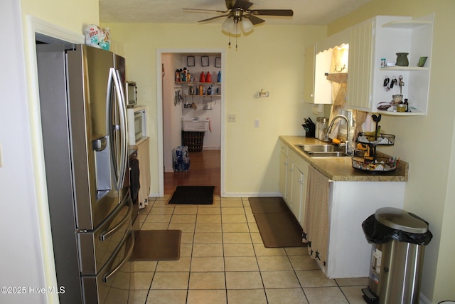 kitchen featuring light tile patterned floors, a sink, a ceiling fan, white cabinetry, and stainless steel appliances
